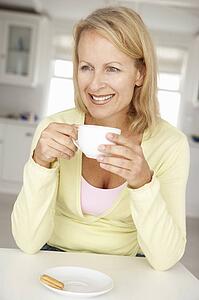 Mid age woman with coffee at home