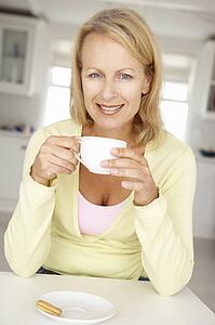 Mid age woman with coffee at home