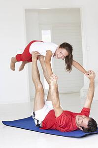 Father and daughter doing yoga lift