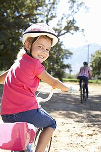 Little girl on country bike ride with mom