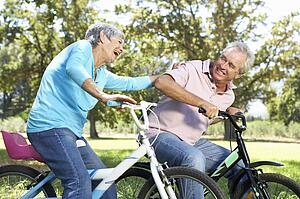 Senior couple playing on children's bikes