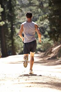 Young man running along country lane