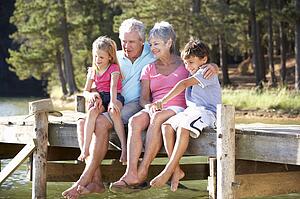 Senior couple sitting by lake with grandchildren
