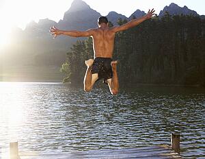 Young man jumping into lake