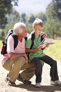 Senior man reading map with grandson on country walk