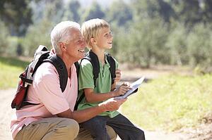 Senior man reading map with grandson on country walk