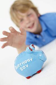 Young boy reaching for piggy bank