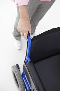 Woman pushing empty wheelchair