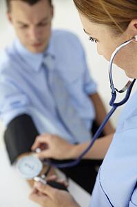 Doctor taking young man's blood pressure