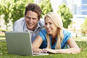 Couple using laptop in city park