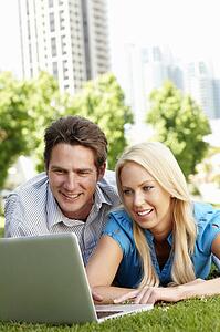 Couple using laptop in city park