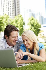 Couple using laptop in city park