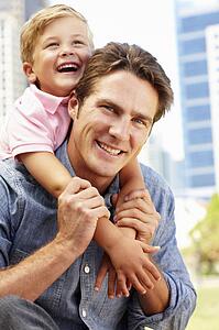 Man sitting in city park with young son