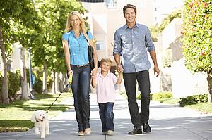 Family walking with dog in city street