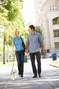 Couple walking with dog in city street