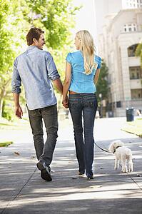 Couple walking with dog in city street