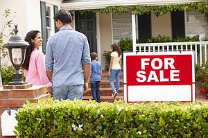 Hispanic family outside home with for sale sign
