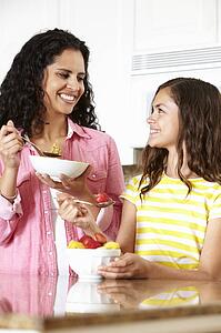 Mother and daughter eating cereal and fruit