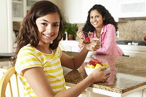 Mother and daughter eating cereal and fruit