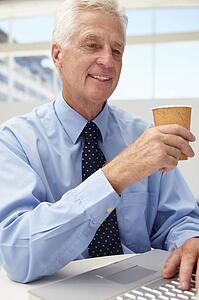 Senior businessman with laptop and coffee