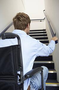 Man in wheelchair at foot of stairs