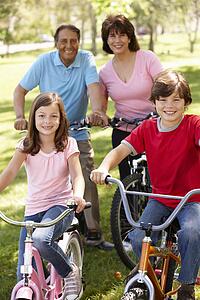 Hispanic family riding bikes in park
