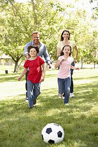 Family playing football in park