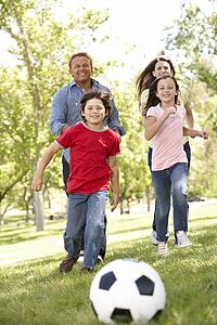 Family playing football in park