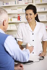 American pharmacist dispensing to senior man