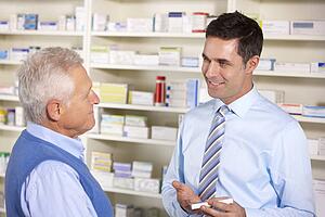 UK pharmacist serving senior man in pharmacy