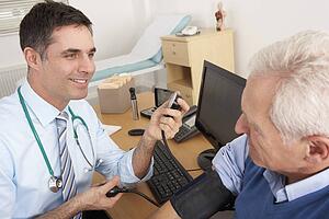 British doctor taking senior man's blood pressure