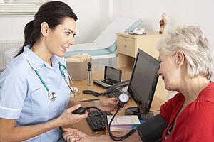 British nurse taking senior woman's blood pressure