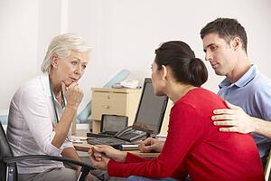 British GP talking to anxious couple in surgery
