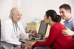 American doctor talking to happy couple in surgery