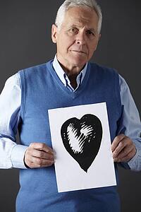 Senior man holding ink drawing of heart