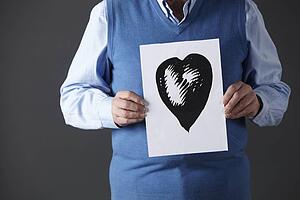 Senior man holding ink drawing of heart
