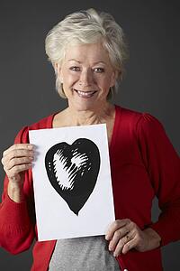 Senior woman holding ink drawing of heart