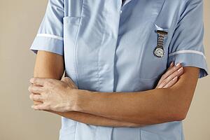 UK nurse standing with arms folded