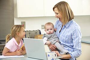 Mother with children using laptop in kitchen