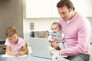 Father with children using laptop in kitchen