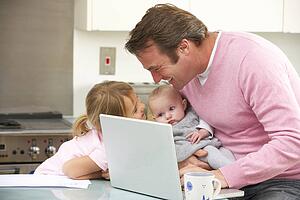 Father with children using laptop in kitchen