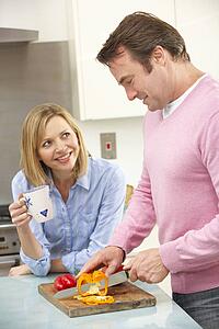 Mature couple preparing meal in domestic kitchen