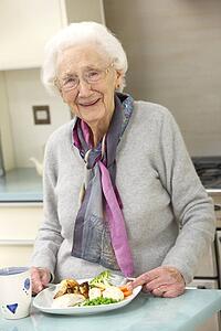 Senior woman enjoying meal in kitchen