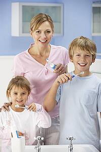 Mother and children cleaning teeth in bathroom