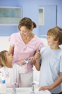 Mother and children cleaning teeth in bathroom
