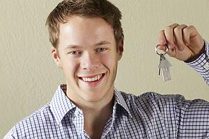 Studio Shot Of Young Man Holding Keys To First Home
