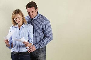 Studio Shot Of Middle Aged Couple Looking at Bills