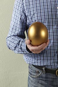 Cropped Studio Shot Of Man Holding Golden Egg