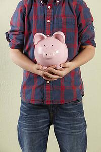 Cropped Studio Shot Of Young Boy Holding Pink Piggy Bank