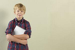 Studio Shot Of Young Boy Holding Tablet Computer